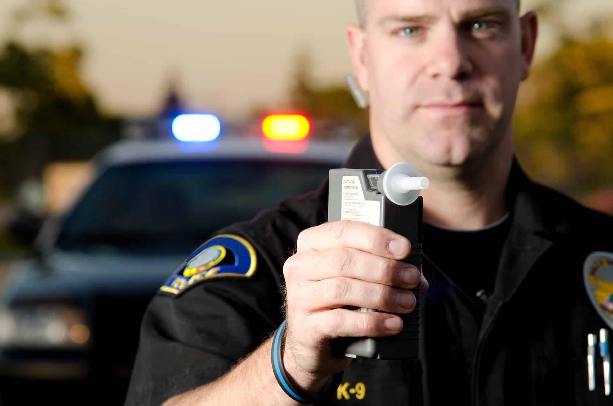 A police officer administers a breathalyzer sobriety test.